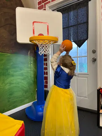 A child in a gown shooting hoops
