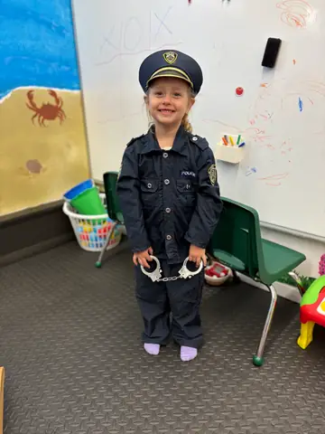 A child smiling in a police officer dress-up costume