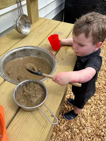 Sifting sand at the mud kitchen