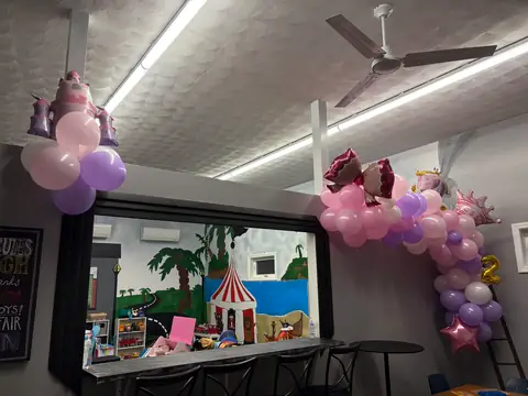 A princess-themed balloon garland hanging above the cafe seating area