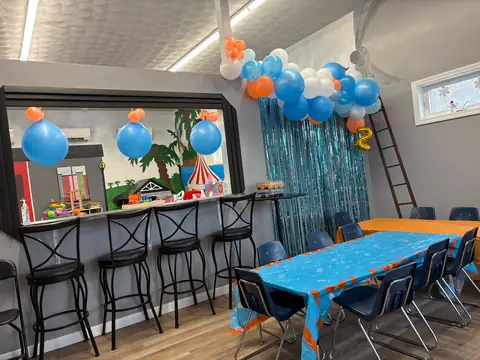 A birthday party room set up with a balloon garland and a long guest table
