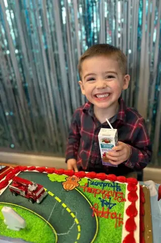 A child blowing out a candle on a fire truck birthday cake