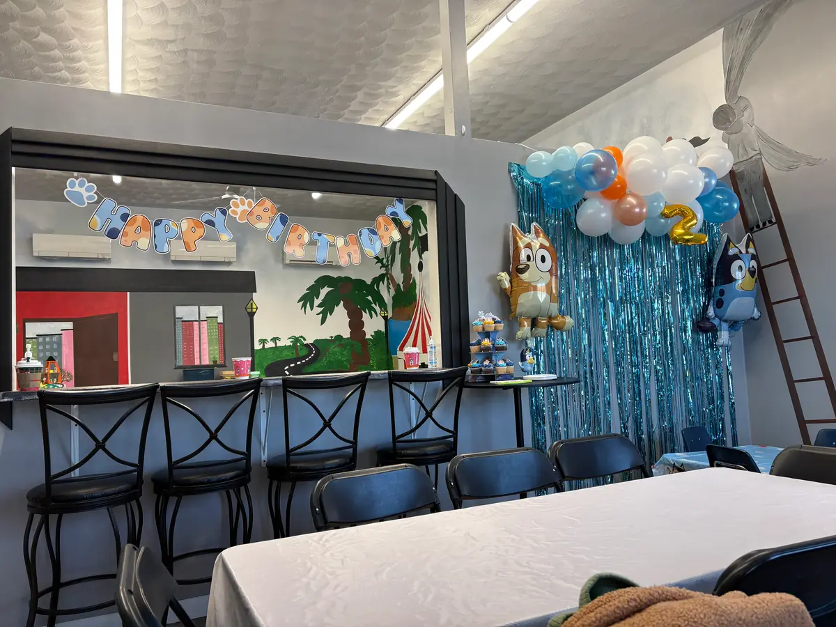 A birthday party set up with a balloon garland and banner